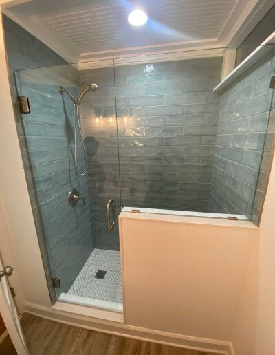 frameless glass shower enclosure with grey subway tile