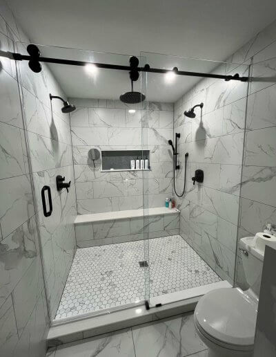 frameless glass shower door with white marble walls