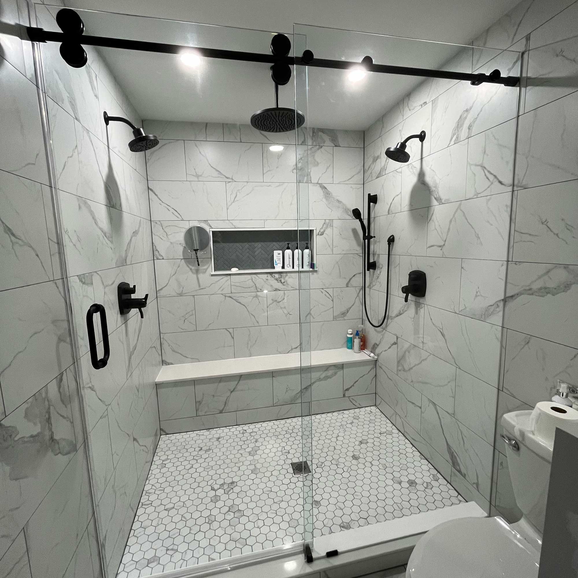 frameless glass shower door with white marble walls