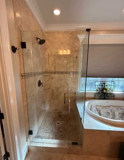 frameless glass shower enclosure with bathtub next to it